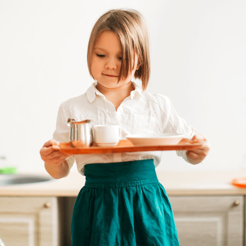 child girl in a linen apron with a tray lays the t umvs3ug min