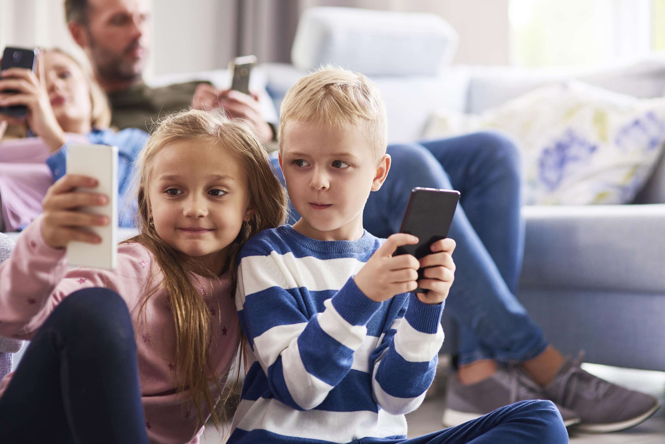 children using mobile phone in living room je48pnz min